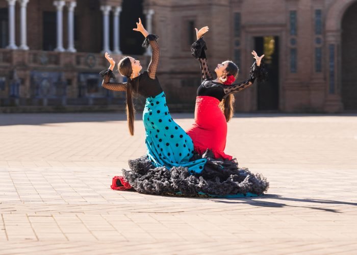 Photo with copy space of two women dressed in flamenco costume doing a choreography in a square