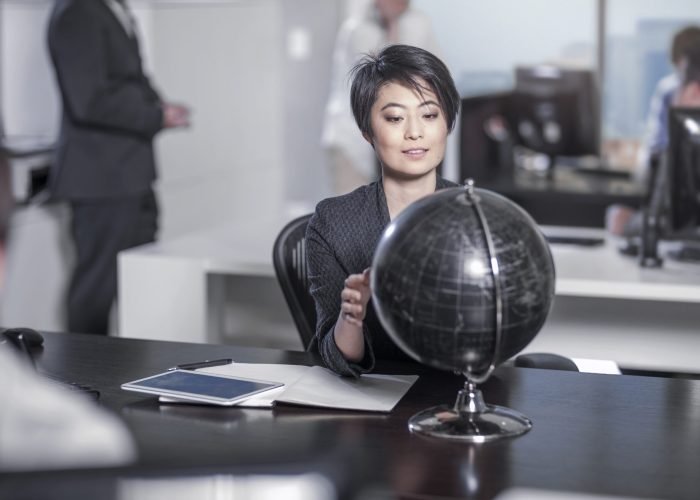 Woman looking at globe sitting at desk in city office